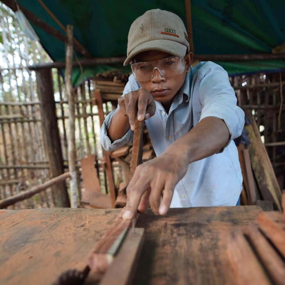 Sarauen carefully sawing a board.